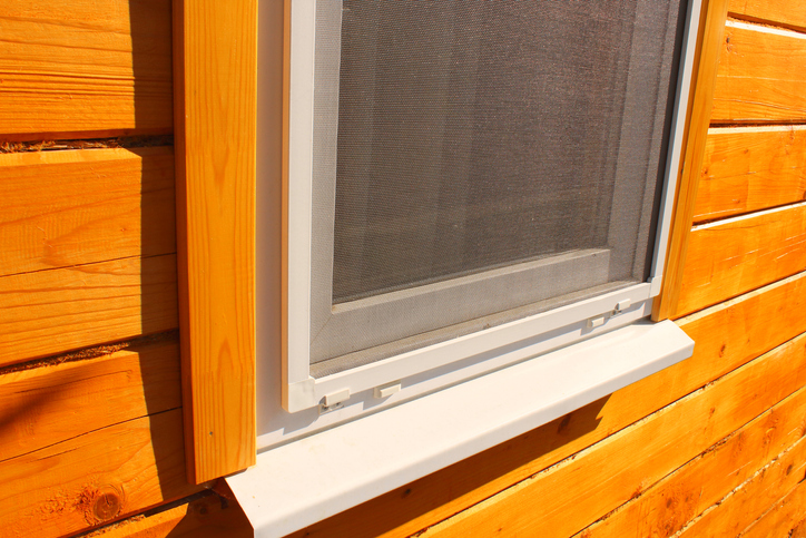moskitiera na plastikowym oknie w drewnianym domu